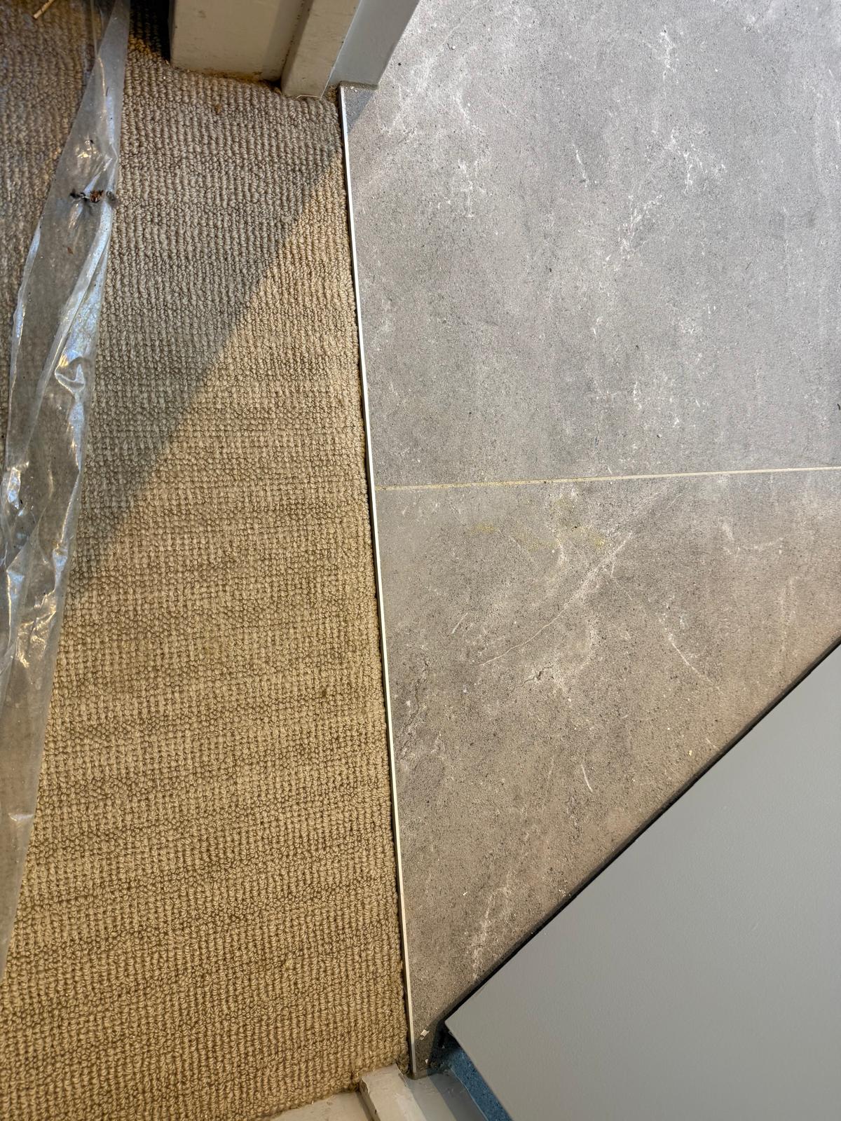 Same threshold finished with a clean, secure carpet edge against the marble tile