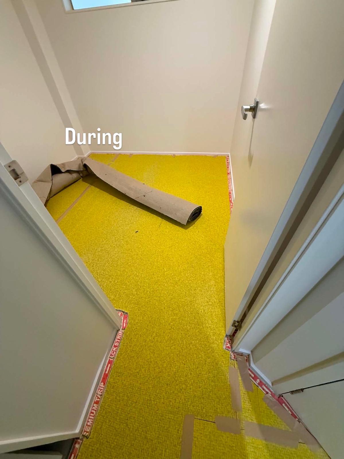 Carpet edge lifted to show the green underlay being fitted at the doorway threshold